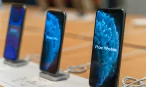 Trois iPhone 11 Pro Max sont alignés sur un présentoir, affichant un fond d'écran bleu abstrait.