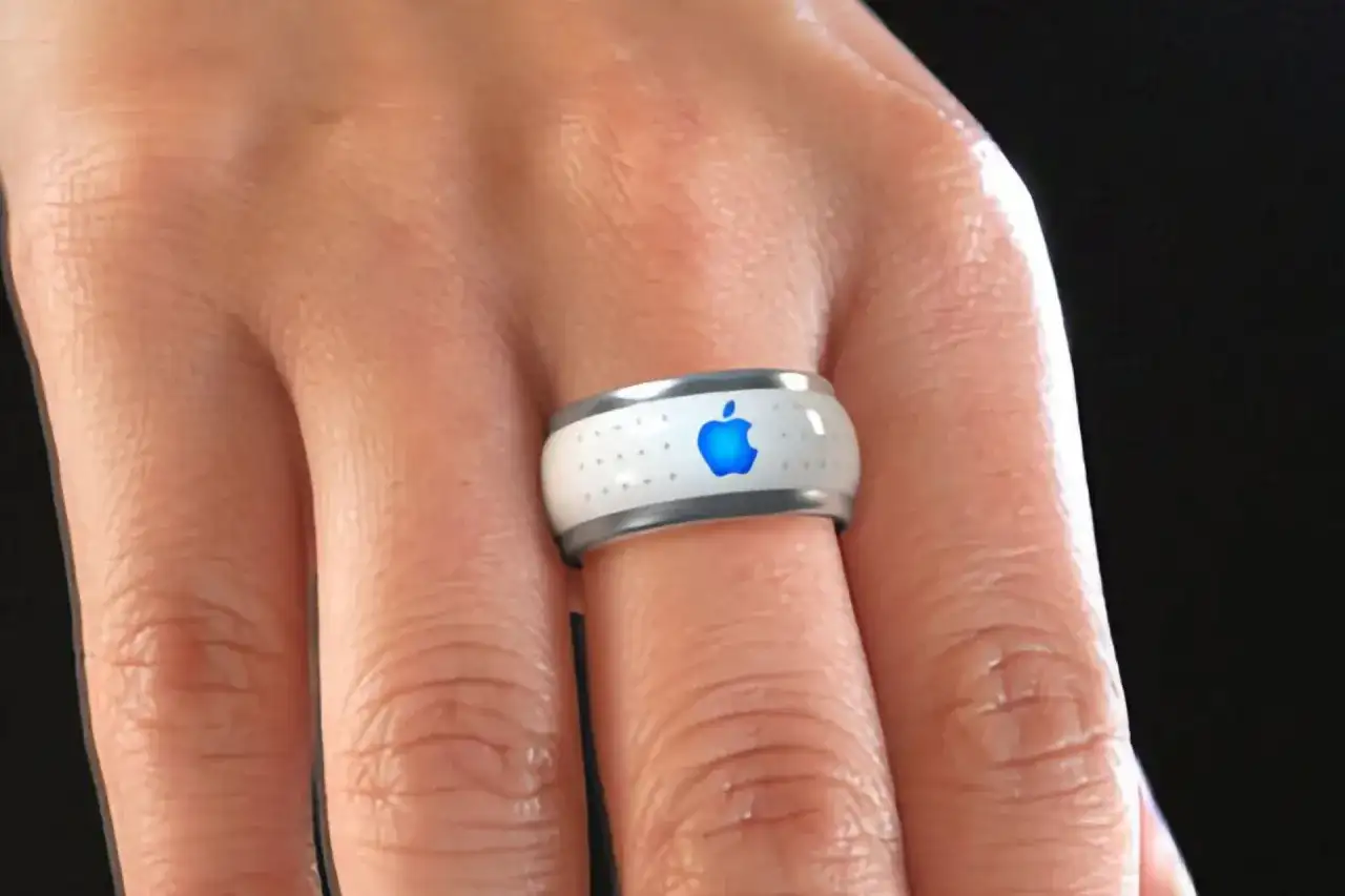 Bague connectée Apple, blanche avec logo bleu lumineux, portée au doigt.