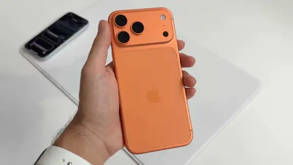 Maintenant, un **iphone avec 4 caméras** orange est tenu dans une main.
